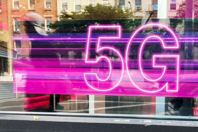 A man walks past an advertisement for 5G cellular phone service in the window of a T-Mobile store in New York City on Tuesday, September 21, 2021. (AP Photo/Ted Shaffrey)