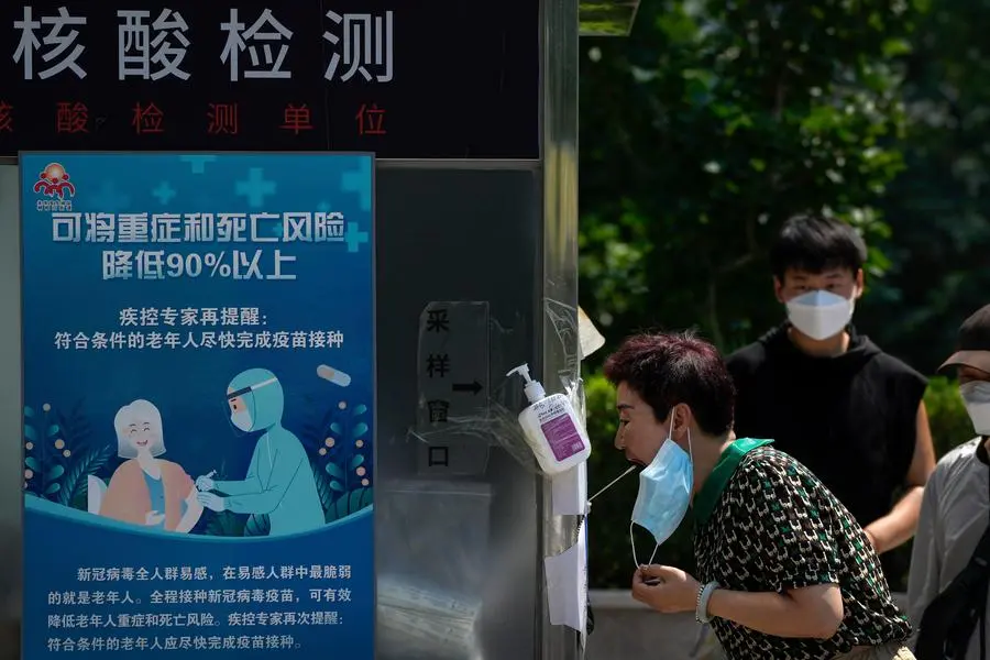 Residents line up to get their routine COVID-19 tests at a testing facility displaying a poster promoting the vaccination in Beijing, Thursday, July 21, 2022. (AP Photo/Andy Wong)