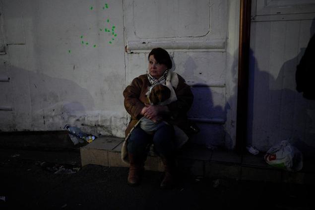 A refugee woman holding her dog sits by the side of the road approaching the border with Poland in Shehyni, Ukraine, Sunday, March 6, 2022. The number of Ukrainians forced from their country increased to 1.5 million and the Kremlin's rhetoric grew, with Russian President Vladimir Putin warning that Ukrainian statehood is in jeopardy. (AP Photo/Daniel Cole)