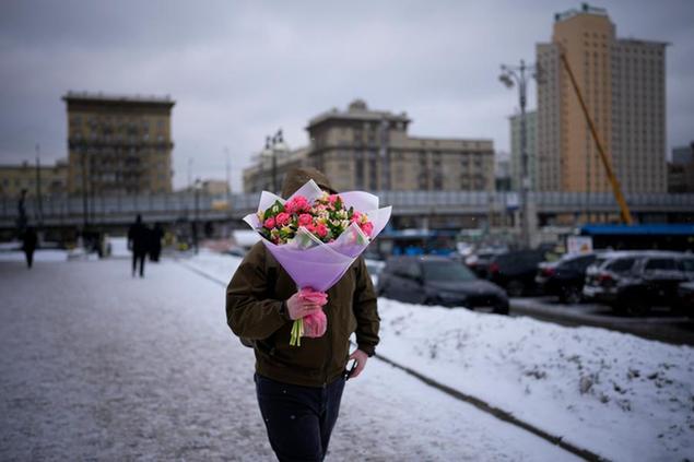 A man carries a bouquet of fresh flowers from a flower market on International Women's Day, in Moscow, Russia, Tuesday, March 8, 2022. International Women's Day on March 8 is an official holiday in Russia, where men give flowers and gifts to female relatives, friends and colleagues. (AP Photo)