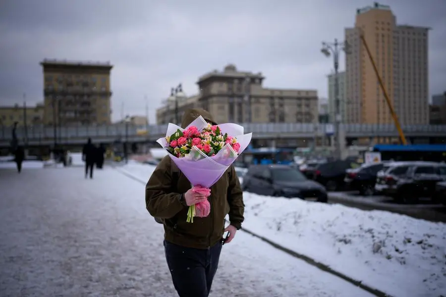 A man carries a bouquet of fresh flowers from a flower market on International Women's Day, in Moscow, Russia, Tuesday, March 8, 2022. International Women's Day on March 8 is an official holiday in Russia, where men give flowers and gifts to female relatives, friends and colleagues. (AP Photo)