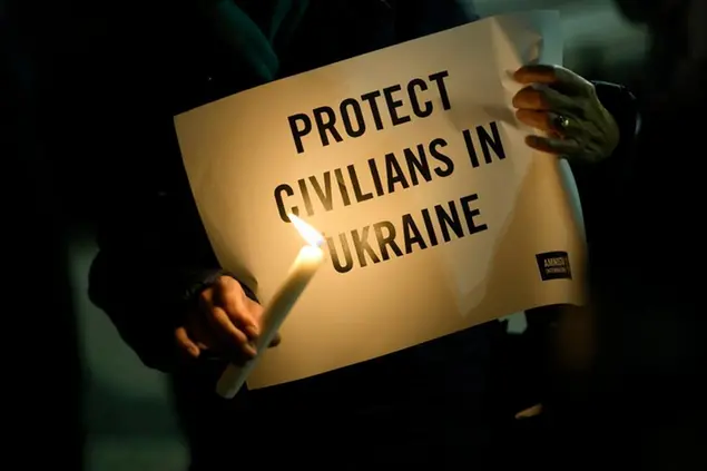 People hold candles and signs during a vigil organized by Amnesty International in solidarity with the Ukrainian people, in Lisbon, Monday, Feb. 28, 2022. There was a tense calm Monday in the Ukrainian capital of Kyiv, but explosions and gunfire were heard in embattled cities in eastern Ukraine as Russia's invasion met unexpectedly stiff resistance. (AP Photo/Armando Franca)