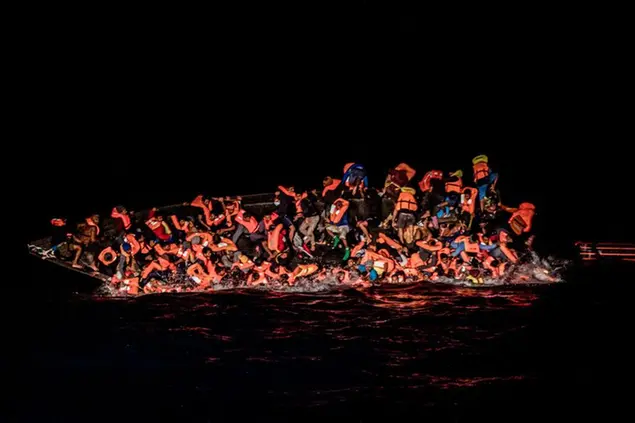 Dozens of migrants fall in the water while they struggle to cling to the side of an upturning boat off the waters of Tunisia early Wednesday, May 25, 2022. Some 110 people were rescued by the non-governmental organization Open Arms during a mission in the Mediterranean Sea. (AP Photo/Valeria Ferraro)