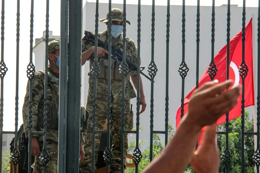 Tunisian soldiers guard the main entrance of the parliament as demonstrators gather outside the the gate in Tunis, Tunisia, Monday, July 26, 2021. Troops surrounded Tunisia's parliament and blocked its speaker from entering Monday after the president suspended the legislature and fired the prime minister following nationwide protests over the country's economic troubles and the government's handling of the coronavirus crisis. (AP Photo/Hedi Azouz)