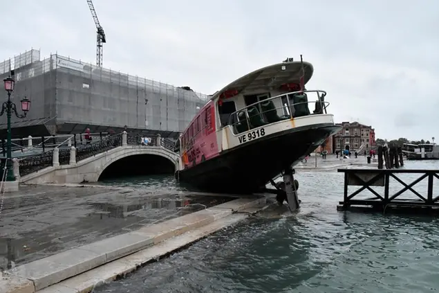 A stranded ferry boat lies on its side, in Venice, Wednesday, Nov. 13, 2019. The mayor of Venice is blaming climate change for flooding in the historic canal city that has reached the second-highest levels ever recorded, as another exceptional water level was recorded Wednesday. (AP Photo/Luigi Costantini)