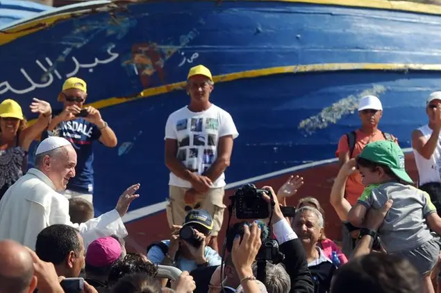 Papa Francesco benedice i fedeli davanti allo scafo di un barcone durante la sua visita a Lampedusa l'8 luglio 2013. ANSA/CIRO FUSCO