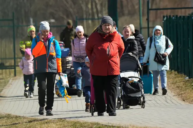 Refugees walk at the border crossing in Medyka, southeastern Poland, after fleeing the war from neighbouring Ukraine, Sunday, March 27, 2022. (AP Photo/Sergei Grits)