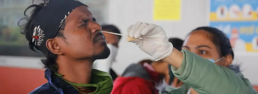 A health worker takes a swab sample of a passenger entering the city to test for COVID-19 at a railway station in Ahmedabad, India, Friday, Dec. 3, 2021. India on Thursday confirmed its first cases of the omicron coronavirus variant in two people and officials said one arrived from South Africa and the other had no travel history. A top medical expert urged people to get vaccinated. (AP Photo/Ajit Solanki)