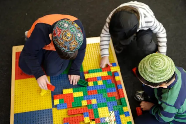 Jewish children wear skull caps, or kippah, in their pre-kindergarten class at the Al & Sonny Gindi Barkai Yeshivah in Brooklyn, New York, Wednesday, March 11, 2015. Starting next September, New York City pre-K classes will be permitted to break in the middle of the day for “non-program” activities such as prayer. Civil liberties groups say the prayer break in a publicly funded classroom may violate the constitutional separation of church and state. (AP Photo/Seth Wenig)