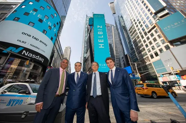 (L-R) Helbiz board member Guy Adami, Founder and CEO of Helbiz Salvatore Palella, Helbiz board member Lee Stern and Chief Financial Officer Giulio Profumo pose outside the Nasdaq MarketSite in Times Square while celebrating being the first U.S. publicly listed shared micro-mobility company on Friday, August 13, 2021 in New York. (Andrew Kelly/AP Images for Helbiz)