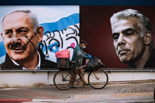 An election campaign billboard for the Likud party that shows a portrait of its leader Prime Minister Benjamin Netanyahu, left, and opposition party leader Yair Lapid, is defaced with Hebrew that reads, \\\\\\\"go home,\\\\\\\" in Ramat Gan, Israel, Sunday, March 21, 2021. Israelis head to the polls on Tuesday for what will be the fourth parliamentary election in just two years. Once again, the race boils down to a referendum on Prime Minister Benjamin Netanyahu. (AP Photo/Oded Balilty)