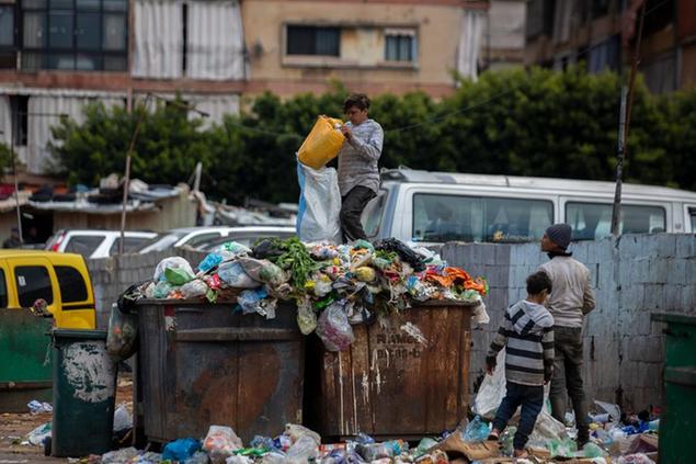 FILE - Children search for valuables in the garbage next to a market in Beirut, Lebanon, Monday, April 12, 2021. Lebanon's severe economic crisis that threw much of the population into poverty is dramatically affecting children leaving some go to bed hungry, lack good medial care and drop out of school to help their families, UNICEF, the U.N. children's agency said Tuesday, Nov. 23, 2021. (AP Photo/Hassan Ammar, File)
