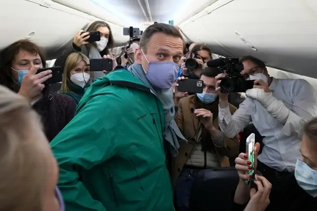 Alexei Navalny is surrounded by journalists inside the plane prior to his flight to Moscow in the Airport Berlin Brandenburg (BER) in Schoenefeld, near Berlin, Germany, Sunday, Jan. 17, 2021. Leading Kremlin critic Alexei Navalny plans to fly home to Russia on Sunday after recovering in Germany from his poisoning in August with a nerve agent. (AP Photo/Mstyslav Chernov)