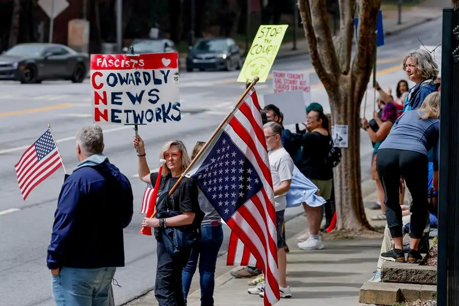 Manifestanti con cartelli e bandiere statunitensi durante una protesta contro la copertura mediatica dell'amministrazione Trump fuori dalla sede della CNN, ad Atlanta