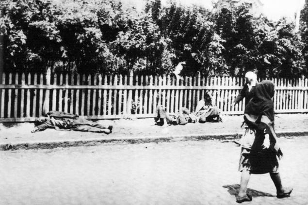 women walk past people dying of starvation in a documentary photograph displayed at an exhibition in kiev, dedicated to holodomor, the great ukrainian famine of early 1930s.