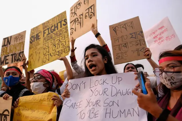 Una manifestante porta un cartello con scritto: \\\"Non chiudere in casa la tua figlia, insegna a tuo figlio ad essere umano\\\" (AP)