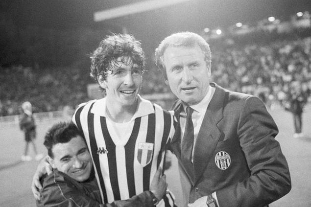 FILE - In this May 30, 1985 file photo, Juventus Turin soccer player Paolo Rossi is embraced by a fan as he stands with Juventus team manager Giovanni Trapattoni on the field of the Brussels Heysel Stadium, May 30, 1985 after winning the European Champions Cup beating FC Liverpool 1-0. Rossi, the star of Italy\\u2019s World Cup-winning team in 1982, has reportedly died at age 64. He was the leading scorer in the \\\\'82 World Cup and was also FIFA\\\\'s player of the year. (AP Photo)