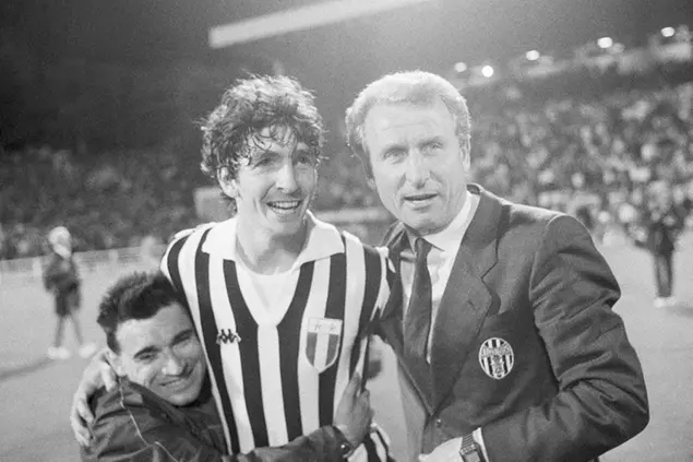 FILE - In this May 30, 1985 file photo, Juventus Turin soccer player Paolo Rossi is embraced by a fan as he stands with Juventus team manager Giovanni Trapattoni on the field of the Brussels Heysel Stadium, May 30, 1985 after winning the European Champions Cup beating FC Liverpool 1-0. Rossi, the star of Italy’s World Cup-winning team in 1982, has reportedly died at age 64. He was the leading scorer in the \\\\'82 World Cup and was also FIFA\\\\'s player of the year. (AP Photo)