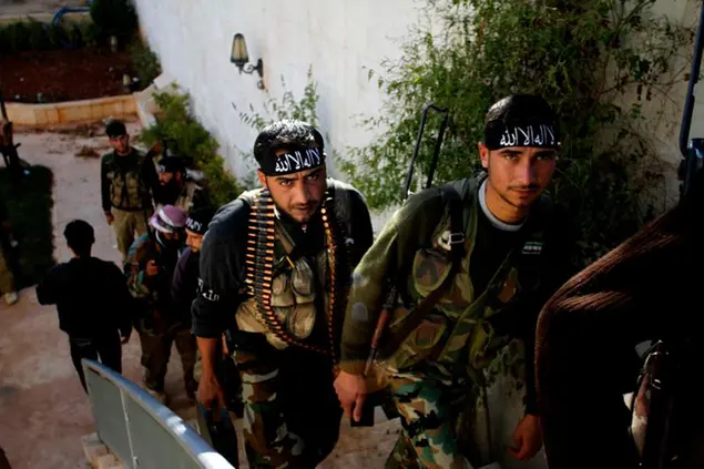 In this Wednesday, Nov. 14, 2012, file photo, Syrian fighters of \\\"The Beloved of Allah,\\\" brigade hold their weapons before fighting with government forces on the outskirts of Aleppo. Syrians are marking 10 years since peaceful protests against President Bashar Assad's government erupted in March 2011, touching off a popular uprising that quickly turned into a full-blown civil war. (AP Photo/Khalil Hamra, File)