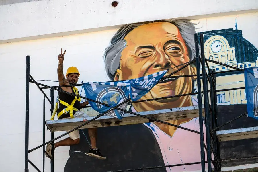 A worker flashes a victory sign, representing the Peronist Party, from a scaffolding as he paints a mural of former Argentine President Nestor Kirchner, the late husband of current Vice President Cristina FernÃ¡ndez de Kirchner, on a government building near the federal court in Buenos Aires, Argentina, Tuesday, Feb. 15, 2022. At the court, current Argentine President Alberto Fernandez made an unusual court appearance to defend his vice president â€” and former chief â€” calling allegations of corruption during her term as head of state â€œa sort of fantasy.â€ (AP Photo/Rodrigo Abd)