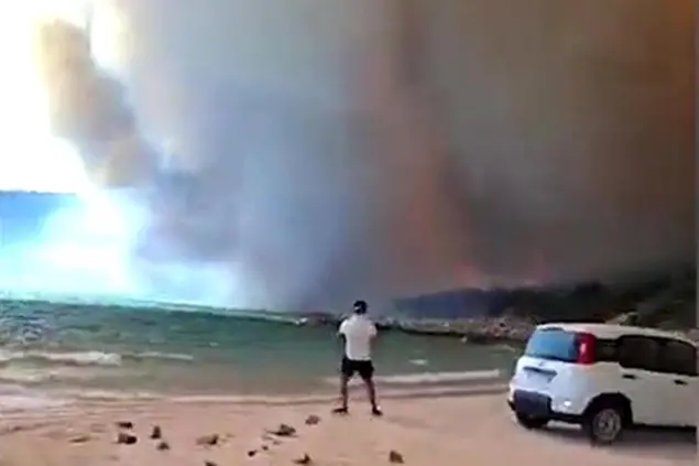 A Punta Molentis nell'area di Villasimius le fiamme sono arrivate a ridosso della spiaggia, bloccando alcuni bagnanti che hanno portato le loro automobili vicino alla riva (foto Ansa)