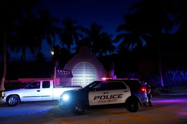 Un sostenitore dell'ex presidente Donald Trump passa davanti alla sua tenuta di Mar-a-Lago, lunedì 8 agosto 2022, a Palm Beach, in Florida, durante la perquisizione dell'Fbi\u00A0(AP Photo/Wilfredo Lee)
