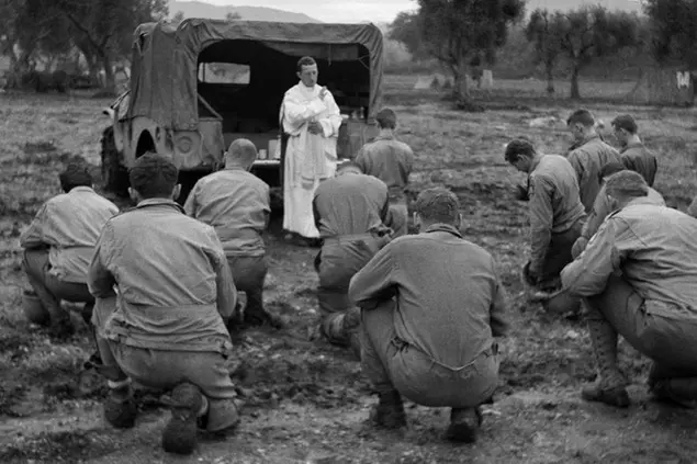 Soldati americani si inginocchiano mentre un prete li benedice nelel campagne italiane, durante la Seconda guerra mondiale, nel dicembre 1943 (AP Photo)