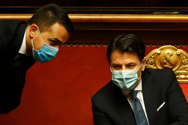 Foreign Minister Luigi Di Maio, left, and Premier Giuseppe Di Maio talk during a debate prior to a confidence vote at the Senate, in Rome, Tuesday, Jan. 19, 2021. Conte fights for his political life with an address aimed at shoring up support for his government, which has come under fire from former Premier Matteo Renzi's tiny but key Italia Viva (Italy Alive) party over plans to relaunch the pandemic-ravaged economy. (AP Photo/Alessandra Tarantino, pool)