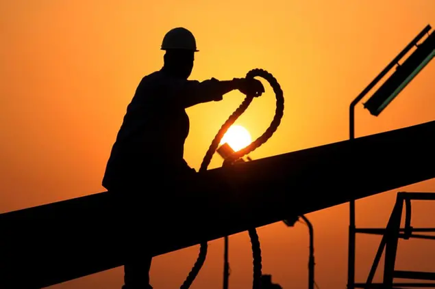 FILE - In this file photo taken July 7, 2010, an unidentified oilfield worker ties pipes to be raised on an oil rig as the sun sets in the Persian Gulf desert oil field of Sakhir, Bahrain. Exxon earned the majority of its income from exploration and production operations in foreign waters, particularly in Africa, Asia and the Middle East. Exxon's results showed a jump in profits across its exploration and production, refining and chemicals businesses. (AP Photo/Hasan Jamali, file)