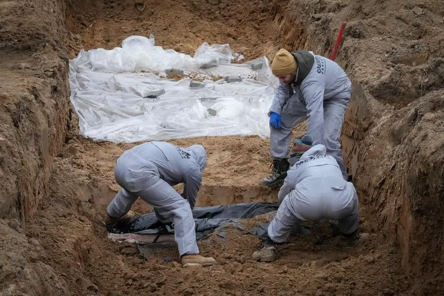 Men wearing protective gear exhume the bodies of civilians killed during the Russian occupation in Bucha, on the outskirts of Kyiv, Ukraine, Wednesday, April 13, 2022. Dozens of bodies of civilians executed by the Russian troops have been exhumed already from the mass grave. (AP Photo/Efrem Lukatsky)