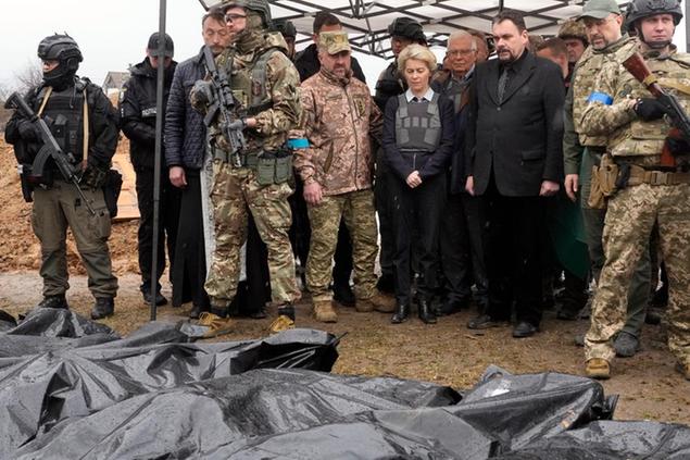 EU Commission President Ursula von der Leyen, center, looks at covered bodies of killed civilians in Bucha, on the outskirts of Kyiv, Ukraine, Friday, April 8, 2022. (AP Photo/Efrem Lukatsky)