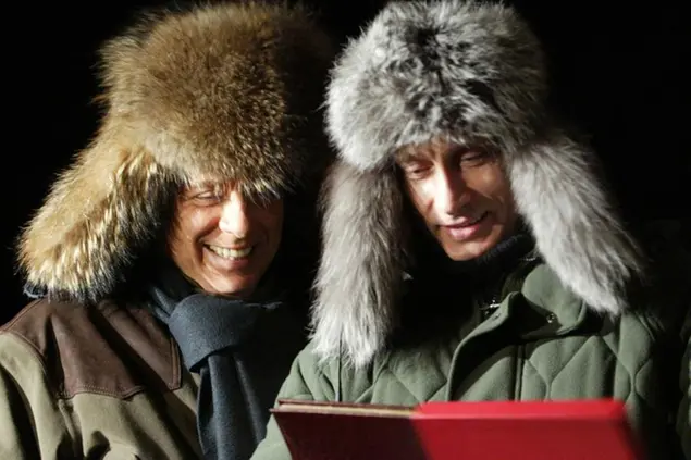FILE - In this Monday, Feb. 3, 2003 file photo, Russian President Vladimir Putin, right, presents a book about his rural lodge Zavidovo to former Italian Prime Minister Silvio Berlusconi in Zavidovo, about 120 kilometers (75 miles) northwest of Moscow. A boast by Berlusconi that his old friend Putin had offered to make him economy minister made headlines around the world this week. (AP Photo/Viktor Korotayev, Pool, File)