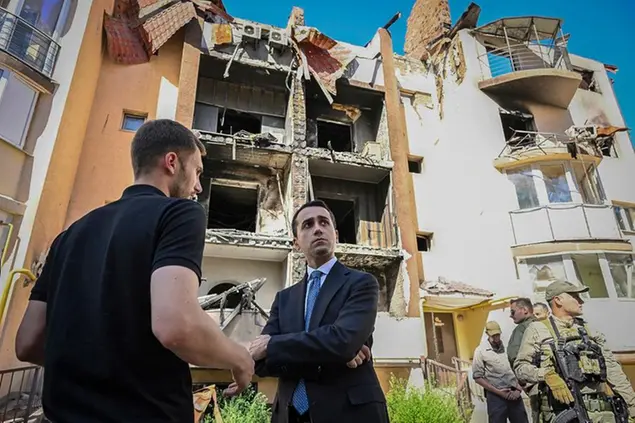 In this image posted on Facebook, Italian foreign minister Luigi Di Maio, center, looks at apartment buildings damaged by shelling, during his visit to Irpin, on the outskirts of Kyiv, Ukraine, Thursday, Aug. 25, 2022. A translator is on left. (Luigi Di Maio Facebook via AP)