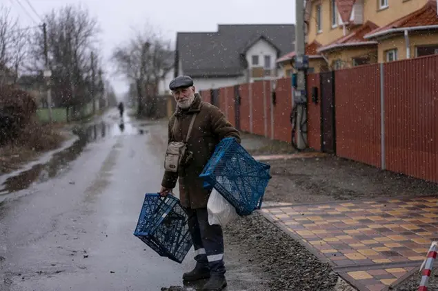 A man looks at reporters while walking under a light snowfall in Bucha, in the outskirts of Kyiv, Ukraine, Sunday, April 3, 2022. (AP Photo/Rodrigo Abd)