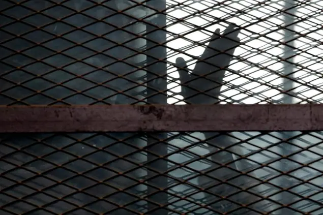 FILE - In this Aug. 22, 2015, file photo, a member of the Muslim Brotherhood waves his hand from a defendants cage in a courtroom in Torah prison, southern Cairo, Egypt. A report released by Amnesty International Wednesday, April 21, 2021, said the number of executions worldwide in 2020 plummeted to its lowest level in at least a decade. But the report said four states in the Middle East â€” Iran, Egypt, Iraq and Saudi Arabia respectively â€” topped the global list and pressed on with shootings, beheadings and hangings, ignoring pleas by rights groups to halt executions during the pandemic. (AP Photo/Amr Nabil, File)