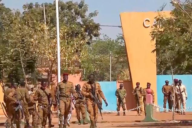 In this image made from video, Burkina Faso mutinous soldiers walk outside the Guillaume Ouedraogo military camp in Ouagadougou, Monday Jan. 24, 2022. Mutinous soldiers said they detained Burkina Faso's President Roch Marc Christian Kabore on Monday, a day after rebellious troops seized a military barracks, setting off a series of gunbattles in the capital of the West African country. (AP Photo)