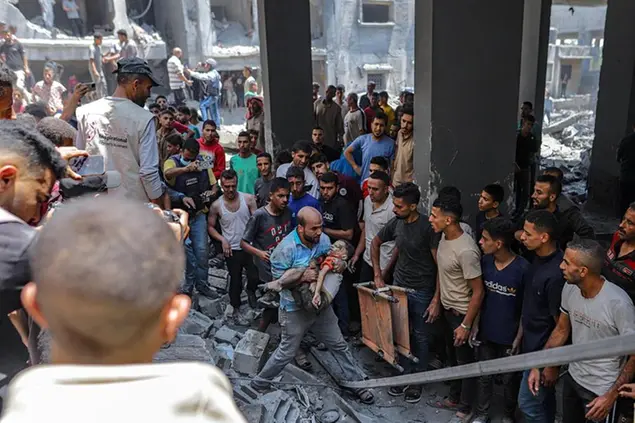 Un bambino tratto in salvo dalle macerie dopo un bombardamento a Gaza