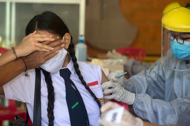 A teenager reacts as she receives a shot of the Sinovac vaccine for COVID-19 during a vaccination campaign at a school in Denpasar, Bali, Indonesia on Monday, July 5, 2021. (AP Photo/Firdia Lisnawati)