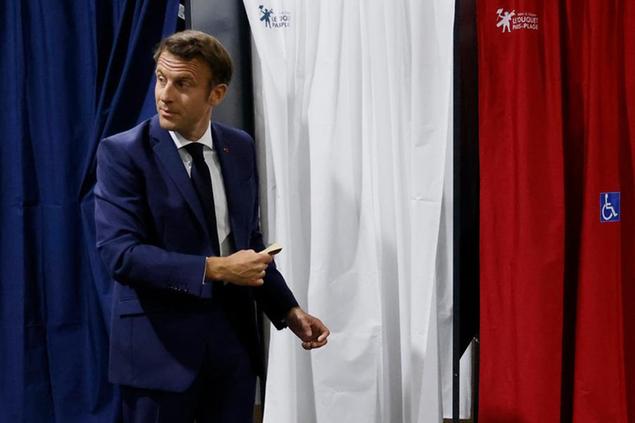 French President Emmanuel Macron enters the voting booth before voting in the first round of French parliamentary election at a polling station in Le Touquet, northern France, Sunday June 12, 2022. French voters are choosing lawmakers in a parliamentary election Sunday as President Emmanuel Macron seeks to secure his majority while under growing threat from a leftist coalition. (Ludovic Marin, Pool via AP)