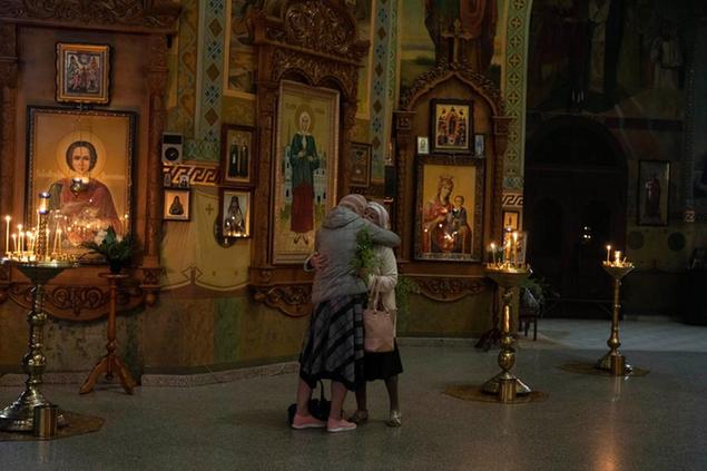 Due donne ucraine si abbracciano durante la celebrazione ortodossa della domenica delle palme (AP)