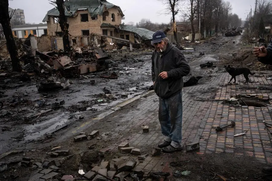 Konstyantyn, 70, smokes a cigarette amid destroyed Russian tanks in Bucha, in the outskirts of Kyiv, Ukraine, Sunday, April 3, 2022. (AP Photo/Rodrigo Abd)