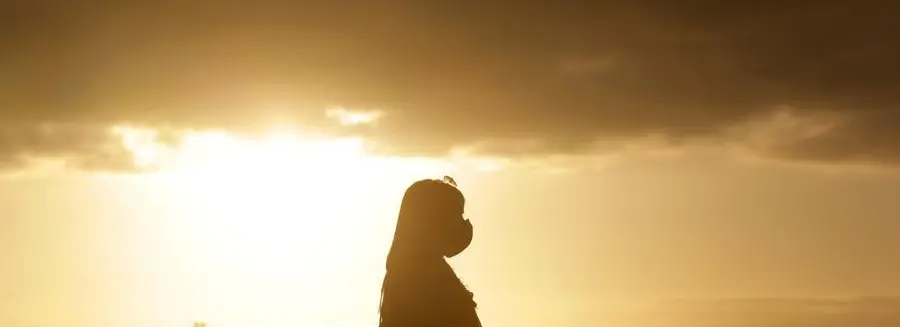 A woman wearing a face mask is silhouetted against the setting sun at a viewpoint overlooking Lisbon center, Monday, Dec. 21, 2020. (AP Photo/Armando Franca)