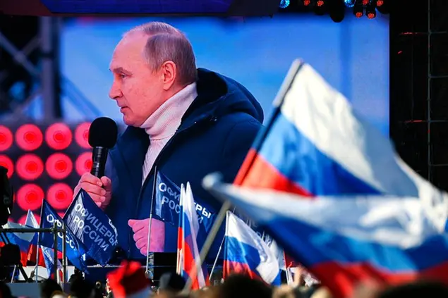 Russian President Vladimir Putin is seen on a big screen as he delivers his speech at the concert marking the eighth anniversary of the referendum on the state status of Crimea and Sevastopol and its reunification with Russia, in Moscow, Russia, Friday, March 18, 2022. (Vladimir Astapkovich/Sputnik Pool Photo via AP)