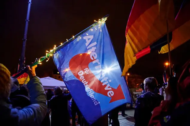 30 October 2020, Brandenburg, Cottbus: A participant waves an AfD flag during a rally of the Islam- and xenophobic Pegida movement in front of the Cottbus Stadthalle. The occasion of the rally is the 6th anniversary of the foundation of the movement. Photo by: Annette Riedl/picture-alliance/dpa/AP Images