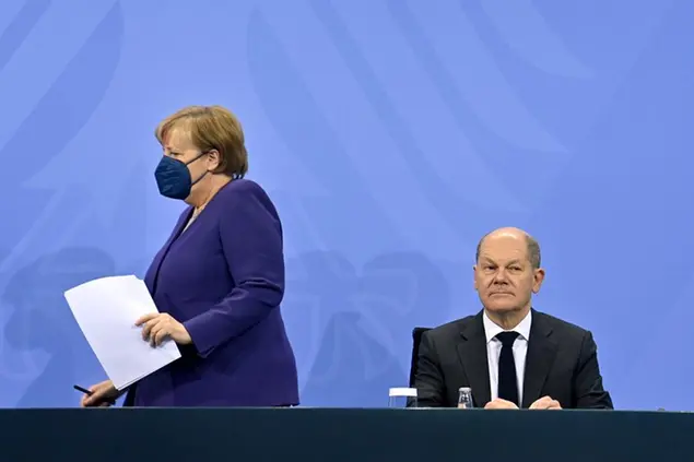 German Chancellor Angela Merkel, left, and Finance Minister Olaf Scholz arrive for a press conference following a meeting with the heads of government of Germany's federal states at the Chancellery in Berlin, Thursday, Dec. 2, 2021. Merkel said Thursday that people who aren't vaccinated will be excluded from nonessential stores, cultural and recreational venues, and parliament will consider a general vaccine mandate, as part of an effort to curb coronavirus infections that again topped 70,000 newly confirmed cases in a 24-hour period. (John Macdougall/Pool Photo via AP)