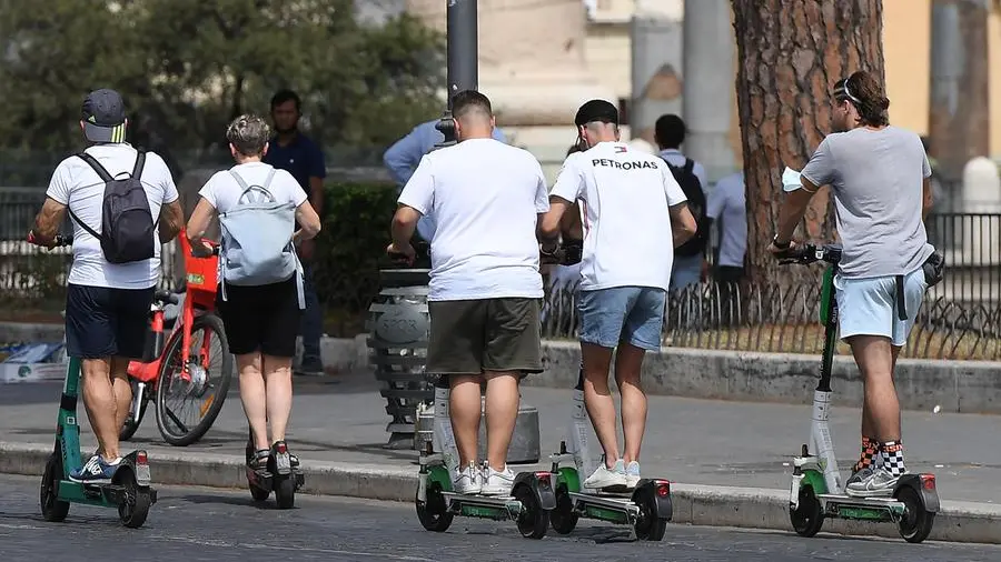 Un gruppo di utenti attende in fila per attivare un pass per le corse gratuite dei monopattini elettrici a Roma, mentre i dipendenti dell'azienda si occupano di gestire le richieste