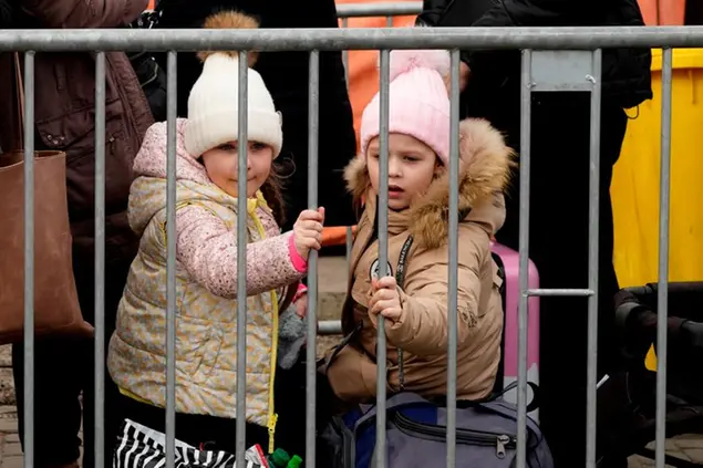 Two young girls look out from in back of a barrier as they wait in a queue after fleeing the war from neighbouring Ukraine, at the border crossing in Medyka, southeastern Poland, on Tuesday, March 29, 2022. The daily number of people fleeing Ukraine has fallen in recent days but border guards, aid agencies and refugees say Russia's unpredictable war offers few signs whether it's just a temporary lull or a permanent drop-off. (AP Photo/Sergei Grits)