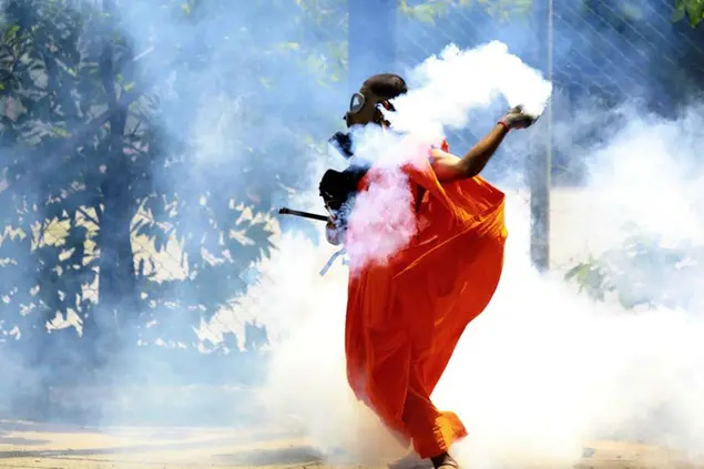 A man throws back a tear gas shell after it was fired by police to disperse the protesters in Colombo, Sri Lanka, Saturday, July 9, 2022. Sri Lankan protesters demanding that President Gotabaya Rajapaksa resign forced their way into his official residence on Saturday, a local television report said, as thousands of people took to the streets in the capital decrying the island nation's worst economic crisis in recent memory. (AP Photo/Amitha Thennakoon)