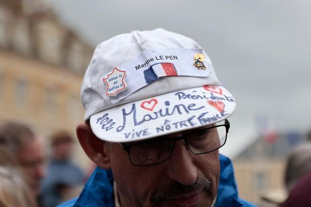 A supporter of French far-right leader Marine Le Pen waits for his candidate to arrive Monday, April 18, 2022 in Saint-Pierre-en-Auge, Normandy. French President Emmanuel Macron is facing off against far-right challenger Marine Le Pen in France's April 24 presidential runoff. (AP Photo/Jeremias Gonzalez)