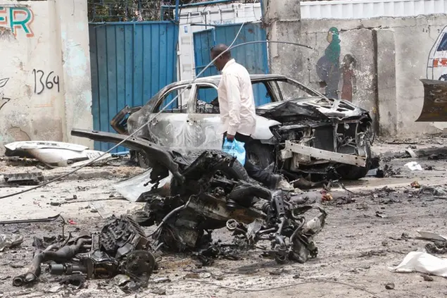 A security officer checks the wreckage after a car bomb attack at a Presidential Palace checkpoint in Mogadishu, Somalia, Saturday Sept. 25, 2021. Police said a vehicle laden with explosives rammed into cars and trucks at a checkpoint leading to the entrance of the Presidential Palace, killing at least eight people. (AP Photo/Farah Abdi Warsameh)